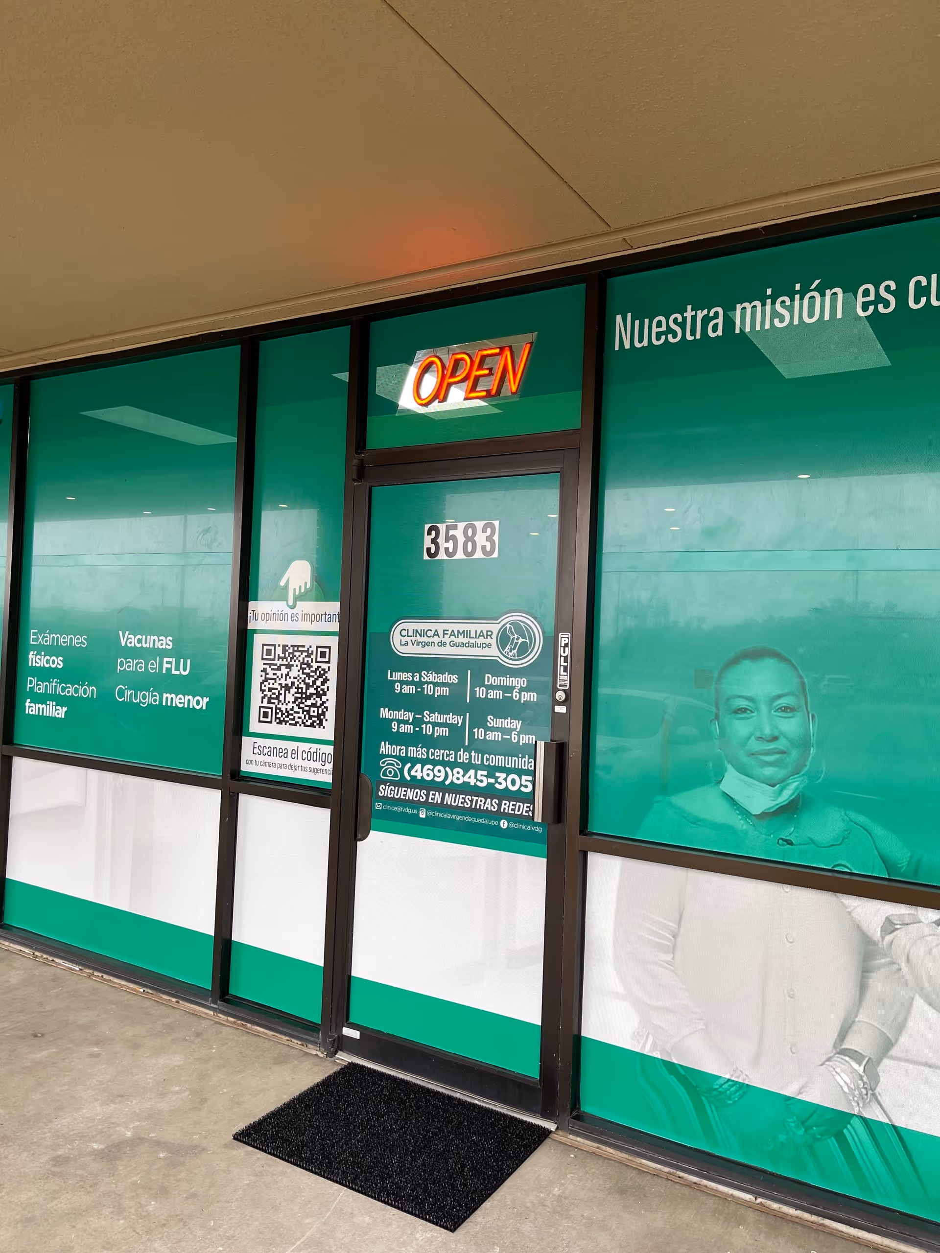 Green storefront signage for Clinica Familiar la Virgen de Guadalupe Irving, with OPEN sign at entrance.