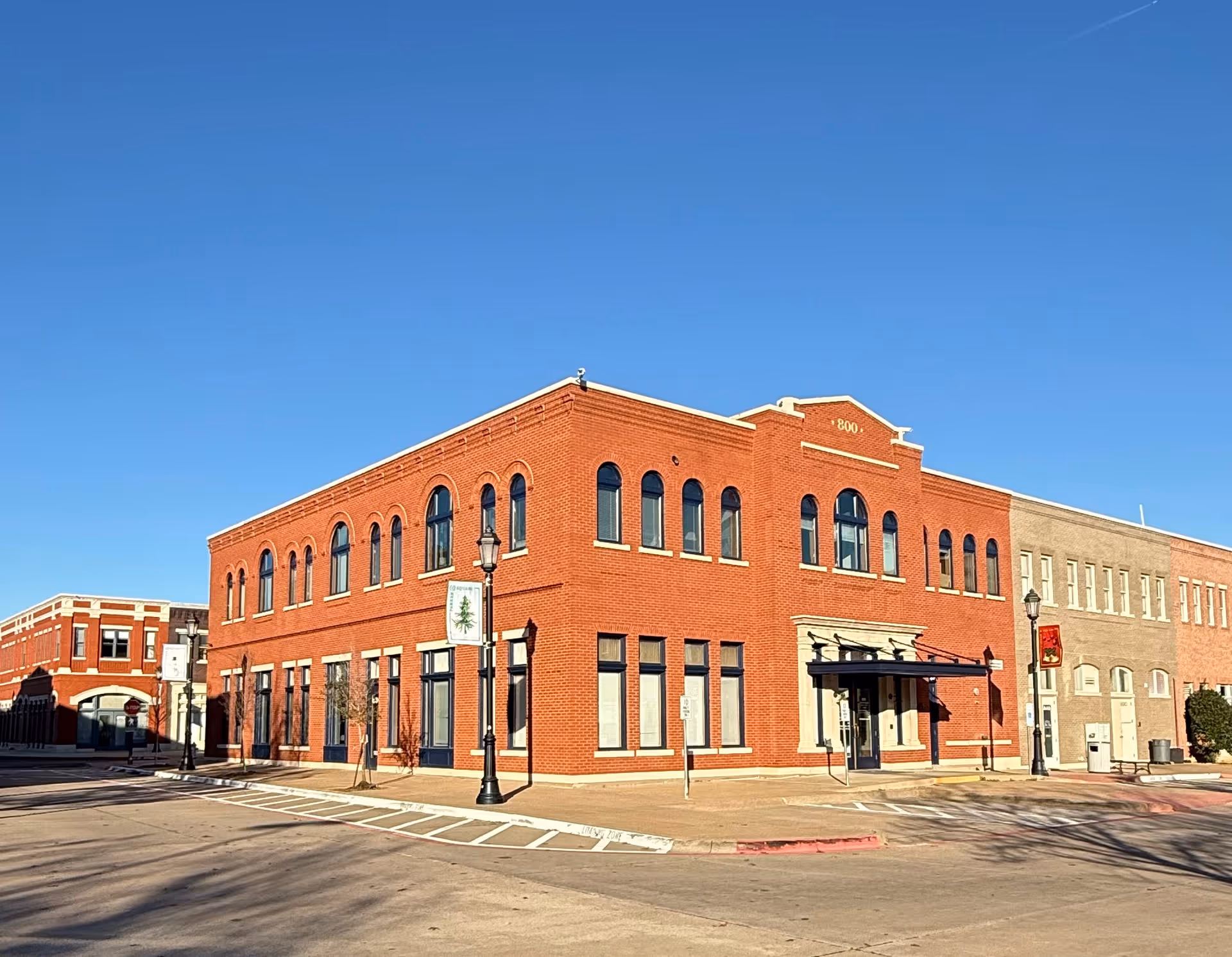 Red brick senior services building with tall arched windows along a quiet street.