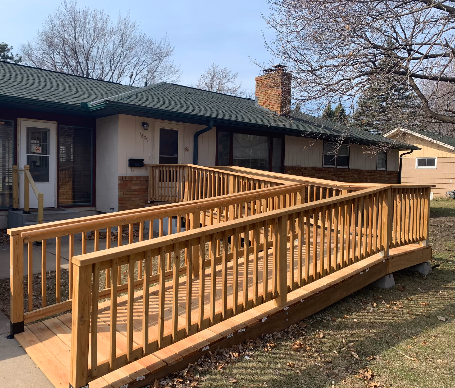 Single-story senior living facility with a wooden wheelchair ramp and front entrance.