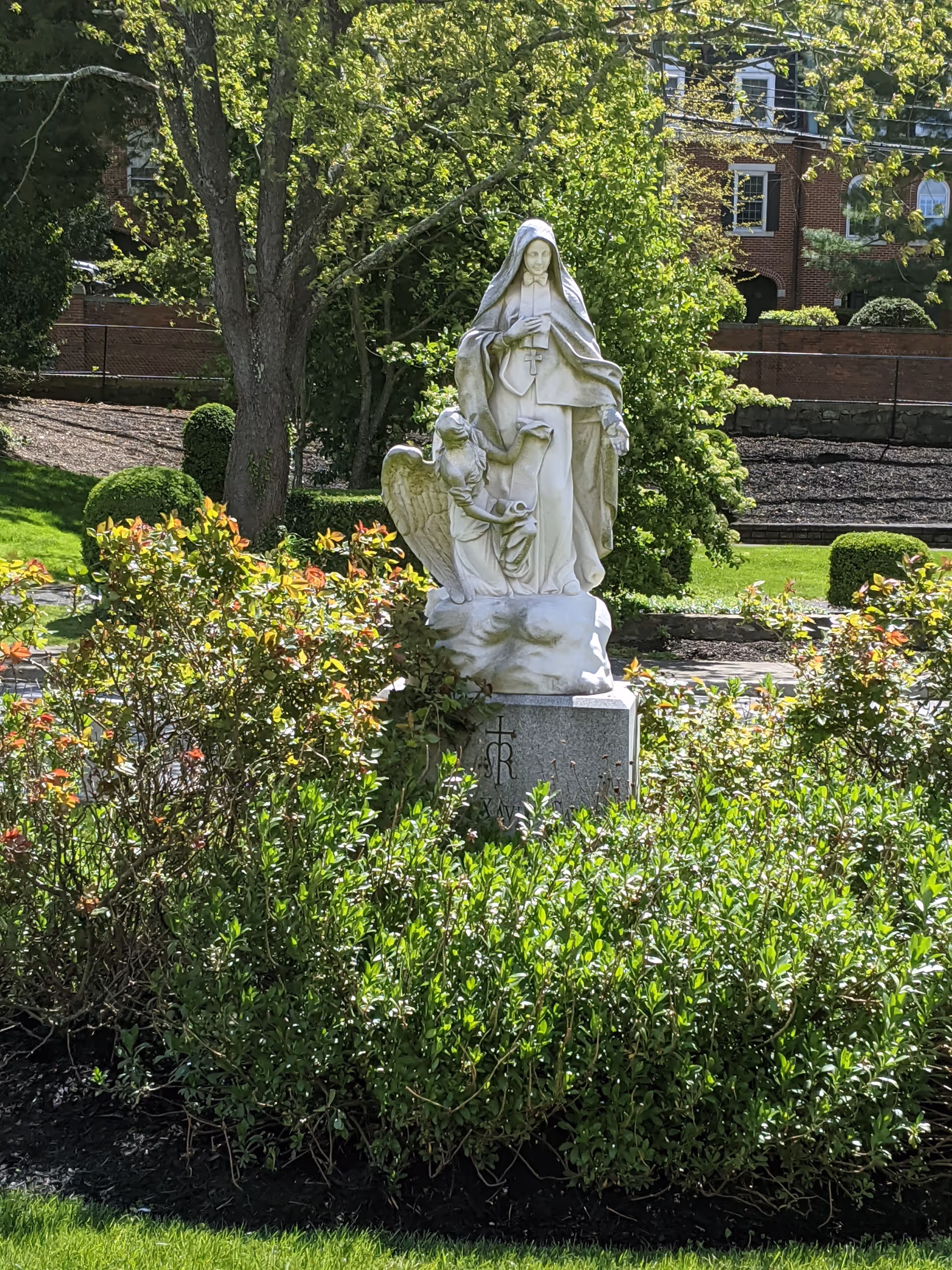 Religious statue of Mary with child in a manicured garden courtyard.