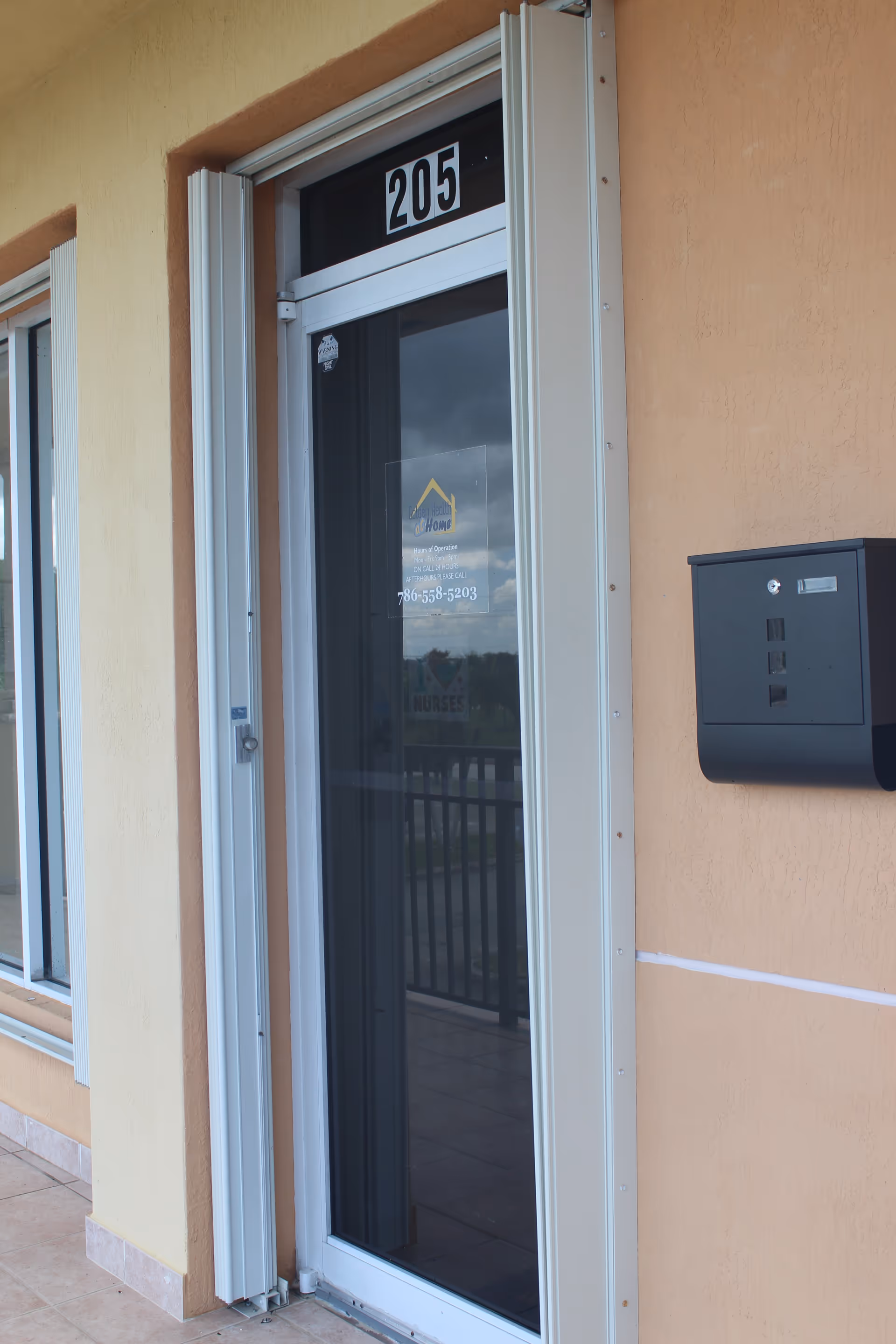 Exterior view of a building entrance with door numbered 205 and a wall mailbox.