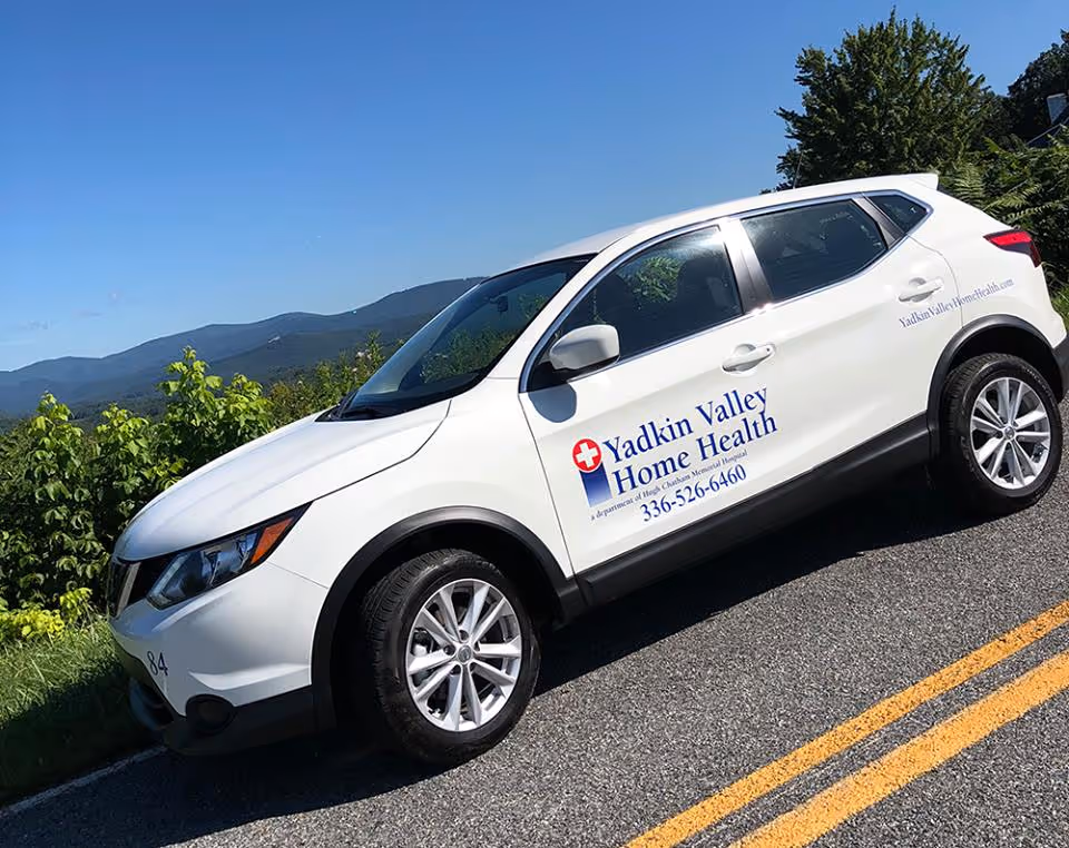 White SUV with Yadkin Valley Home Health logo parked on a mountain road.