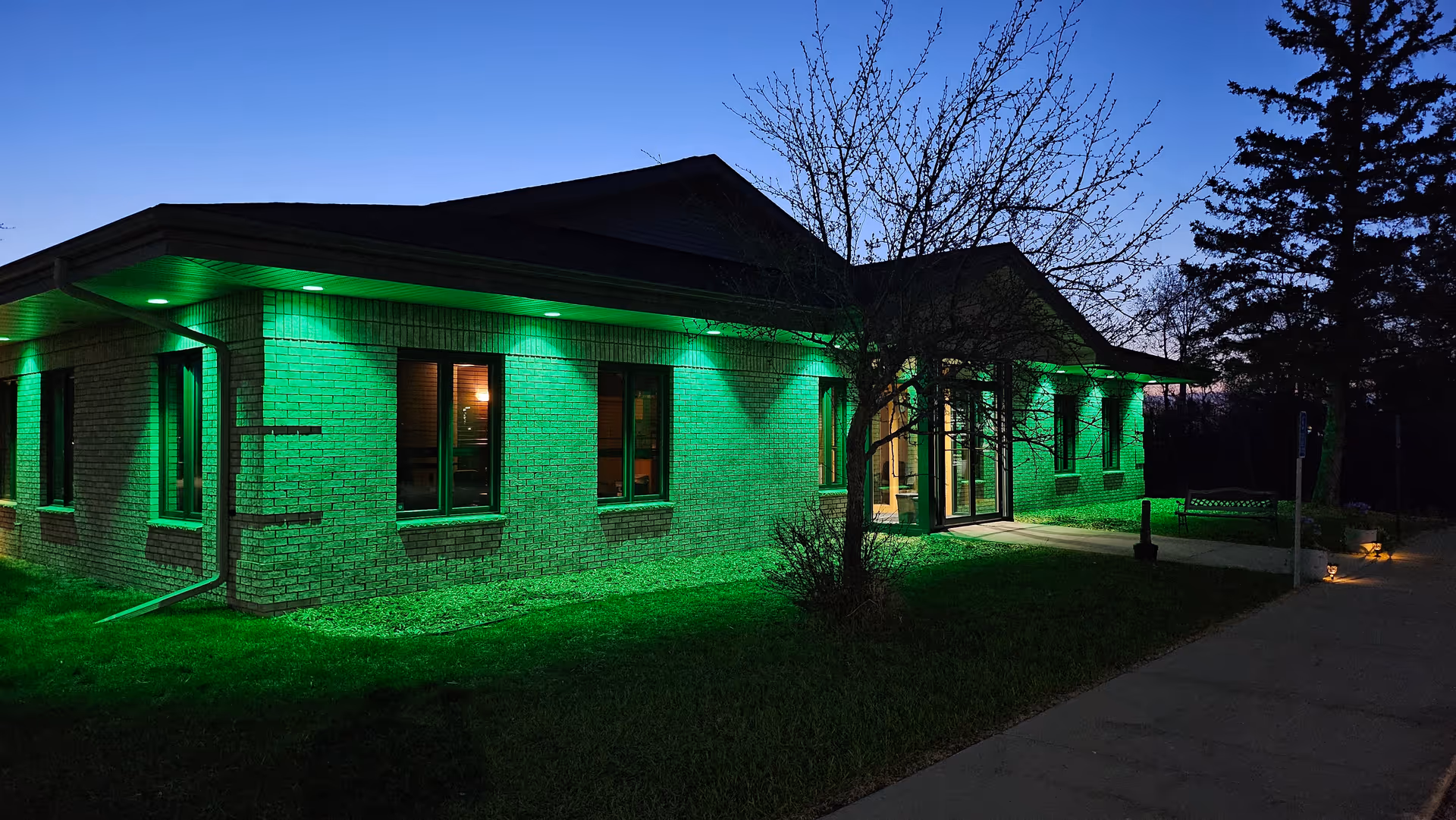 Night exterior of a brick building with green lighting along its walls.