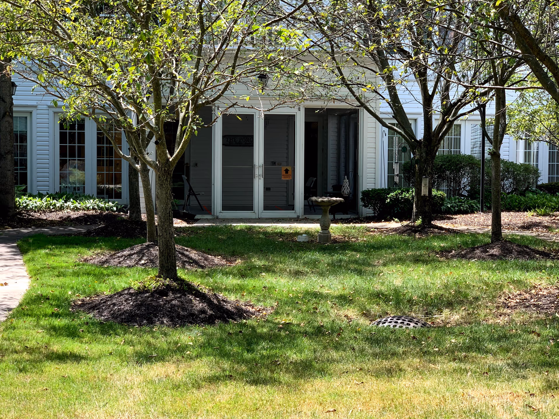 Front exterior of Fairmont Senior Living of Westlake with trees and lawn.