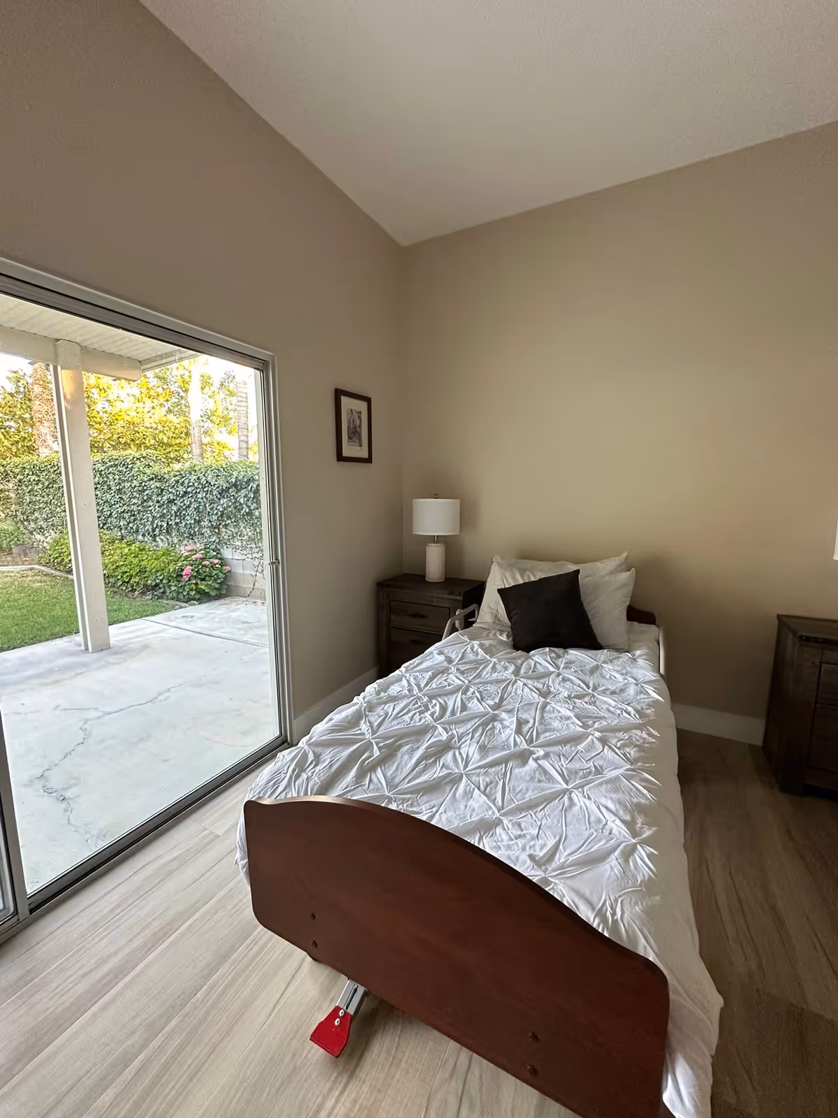 Bedroom with white quilted bed, a bedside lamp, and sliding glass door to patio.