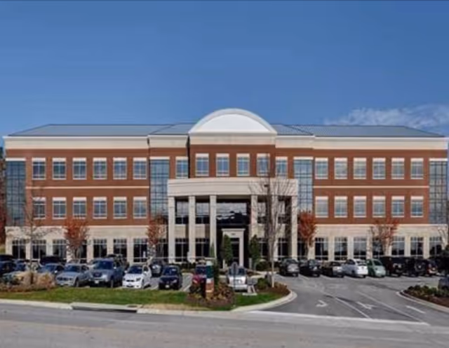 Brick-front senior living facility exterior with central entrance and parking.