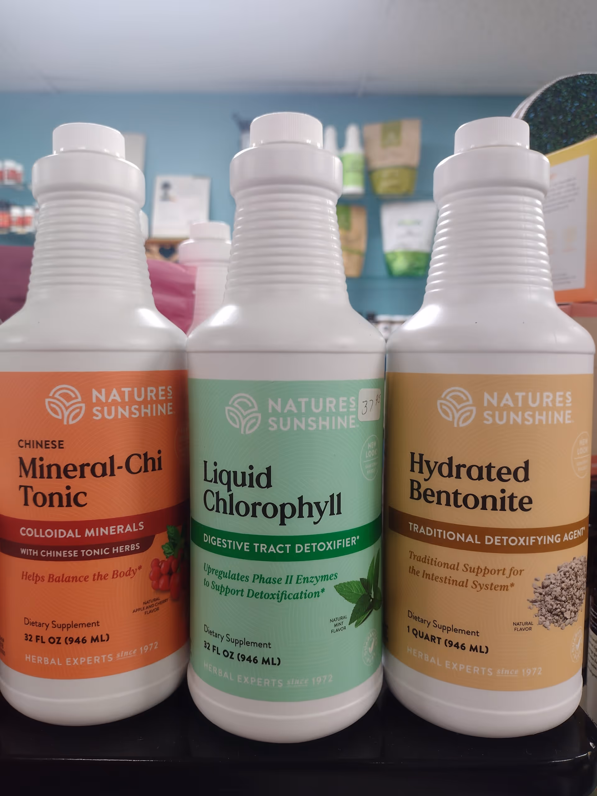 Close-up of three Nature's Sunshine supplement bottles labeled Mineral-Chi Tonic, Liquid Chlorophyll, and Hydrated Bentonite.