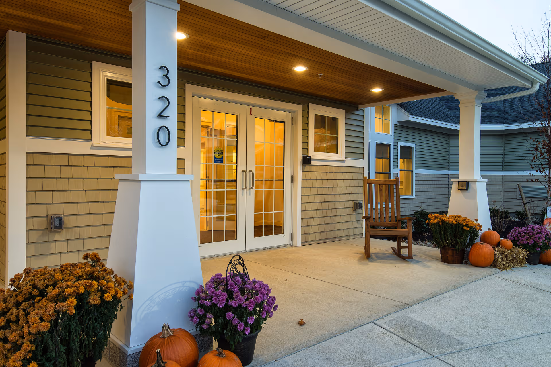 Exterior view of Avita of Stroudwater entrance with pumpkins, mums, and a wooden rocking chair.