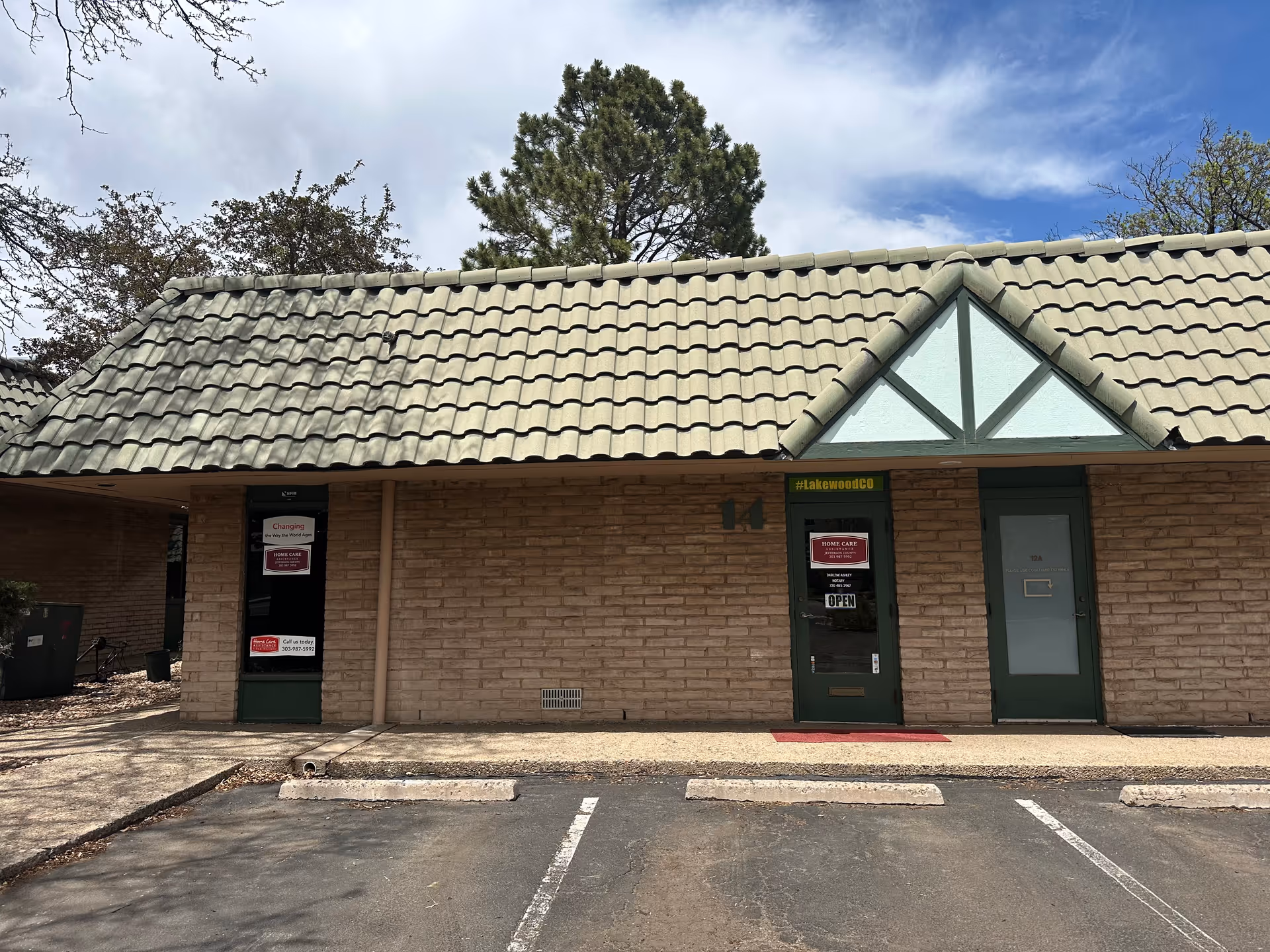 Front exterior of a brick senior care building with doors and a parking lot.