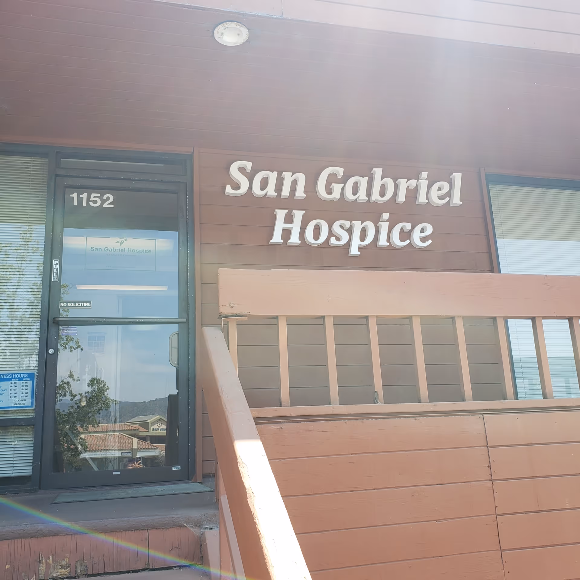 Front exterior of San Gabriel Hospice building with entrance door and railing.