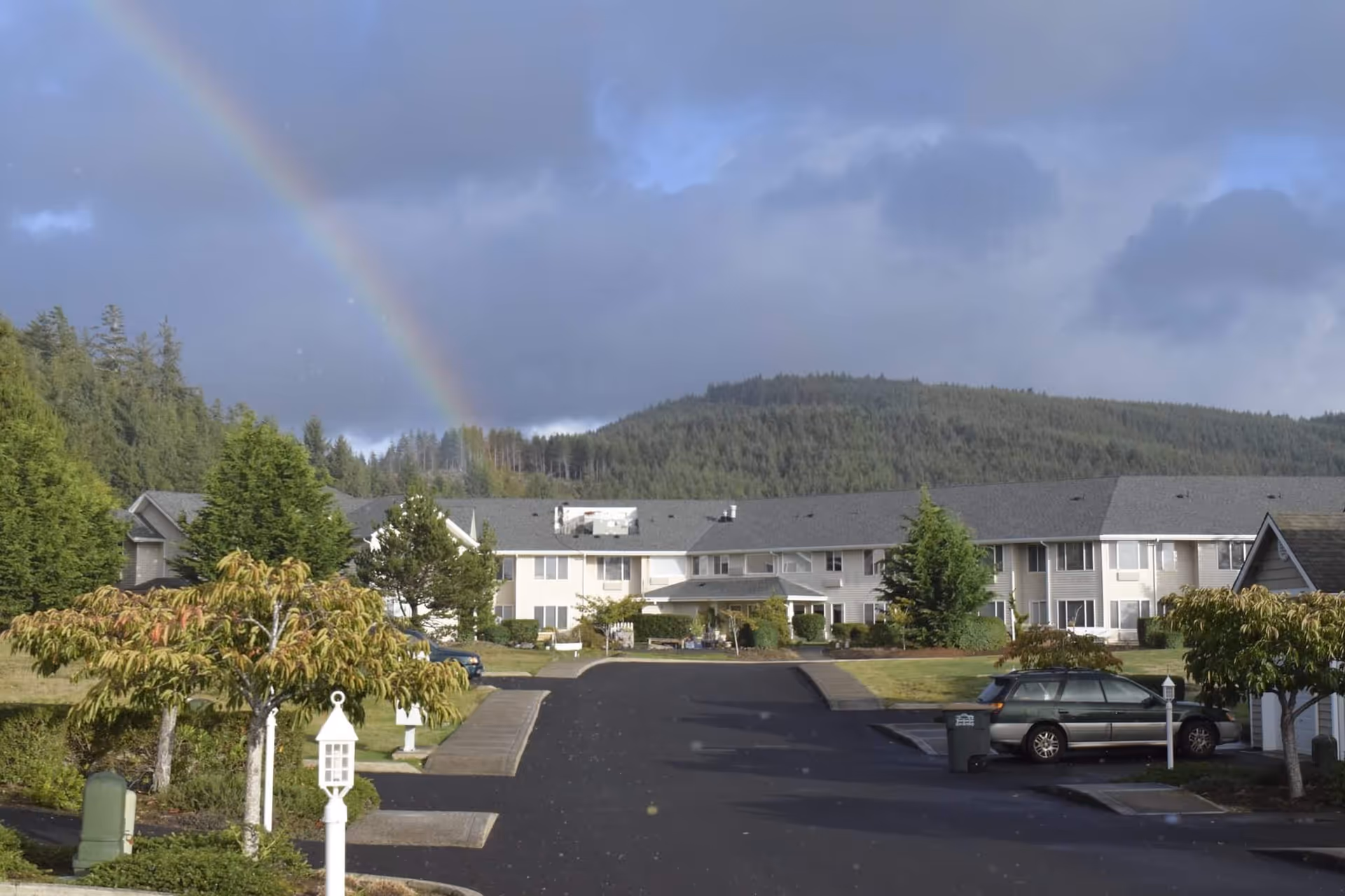 Exterior view of a senior living campus with a rainbow above the buildings.