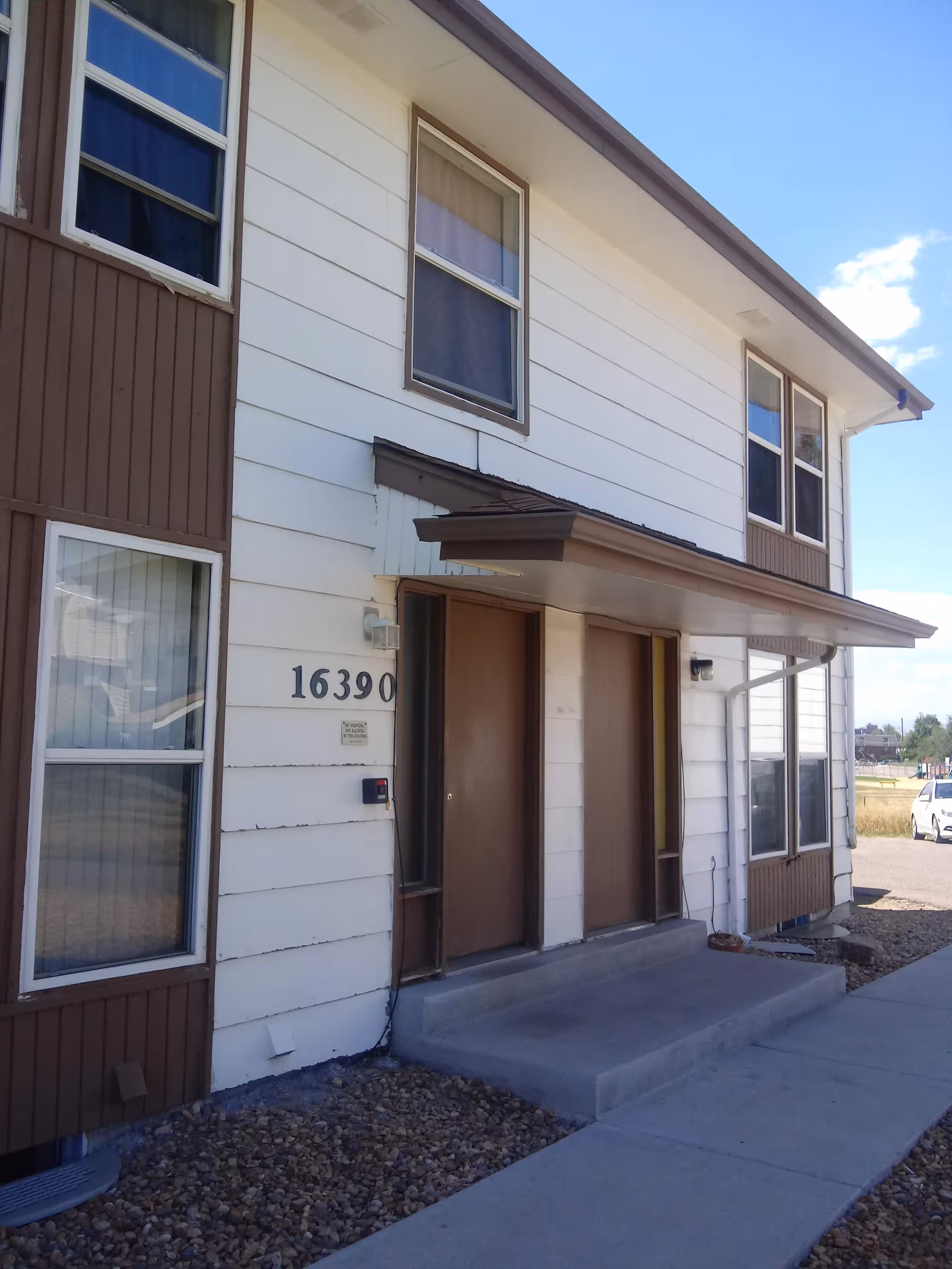 Two-story senior housing building with white siding, brown trim, and an entry canopy.