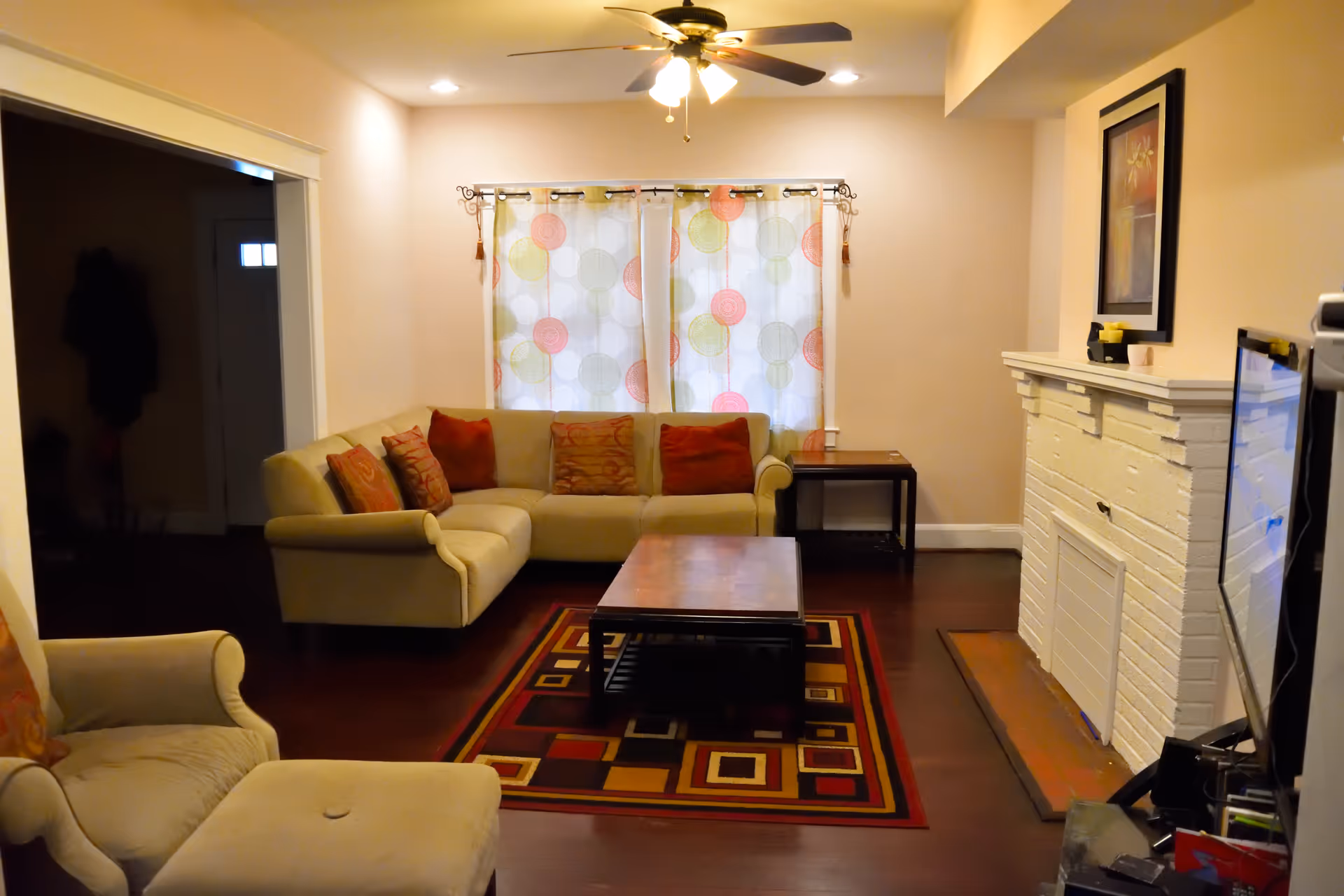 Cozy living room with beige sectional sofa, coffee table, rug, and fireplace.