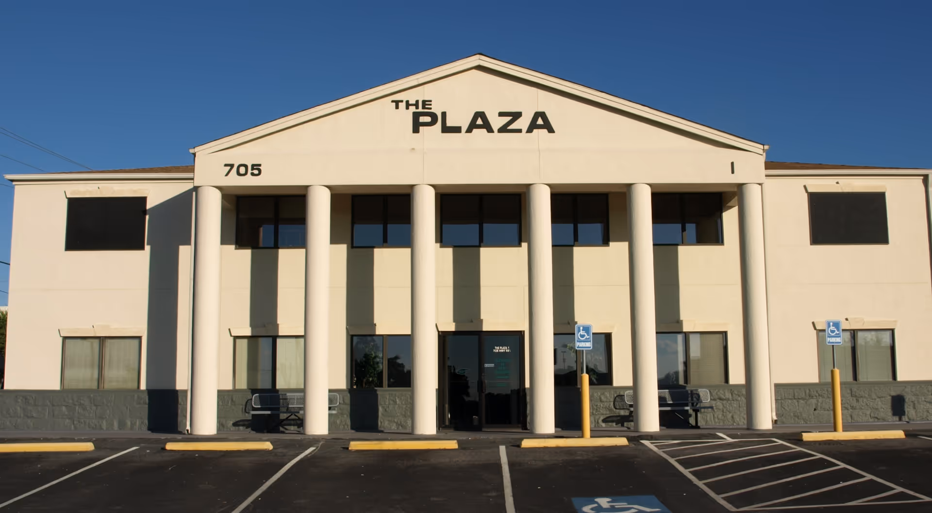 Front exterior of a beige building with tall pillars and 'The Plaza' signage.
