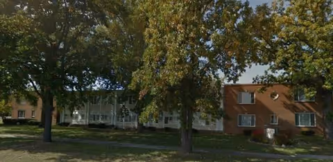 Exterior view of a Medilodge senior living building with trees and a grassy lawn.