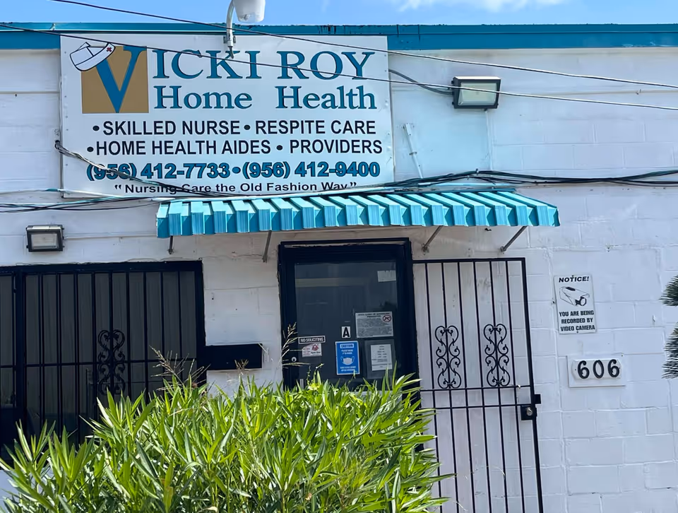 Exterior view of Vicki Roy Home Health building with sign, gate, and greenery