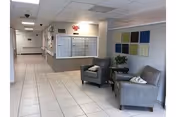 Interior corridor of a senior living lobby with gray seating and colorful wall art.