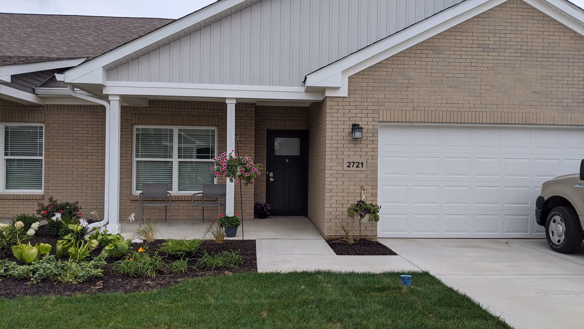 Front exterior of Woodland Terrace of Danville, brick building with covered entry, chairs, and hanging baskets.