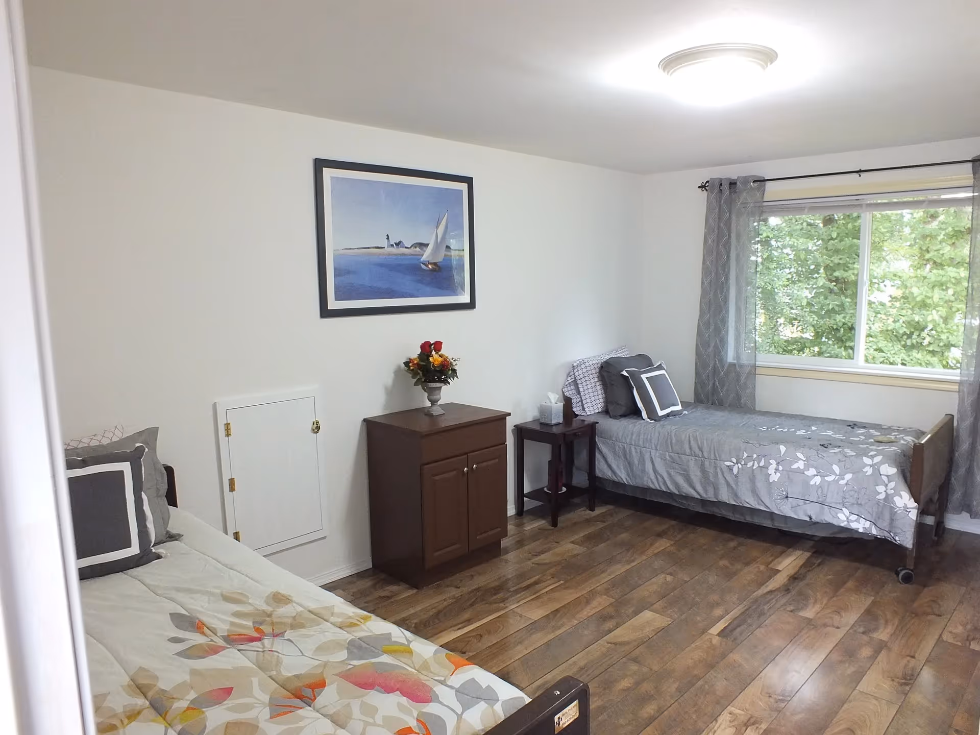 Bright bedroom with two single beds, a dresser, nightstand, and window.