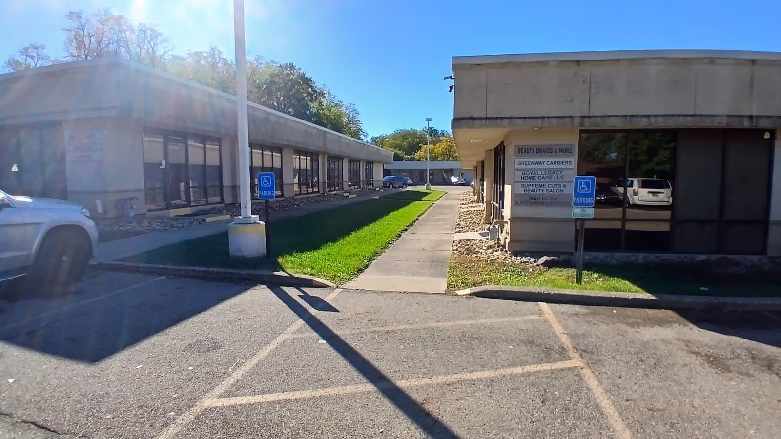 Exterior view of a senior care facility with a central walkway between buildings and parking.