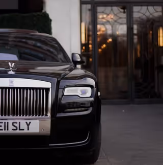 Black Rolls-Royce parked in front of a building entrance with glass doors