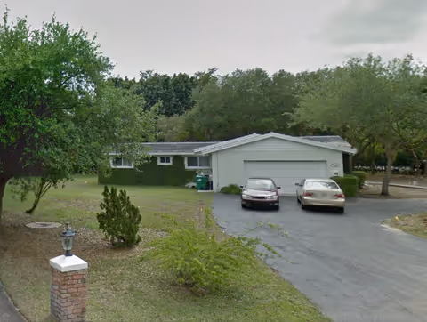 Front exterior of The Chalet at Old Cutler, showing a driveway and parked cars.