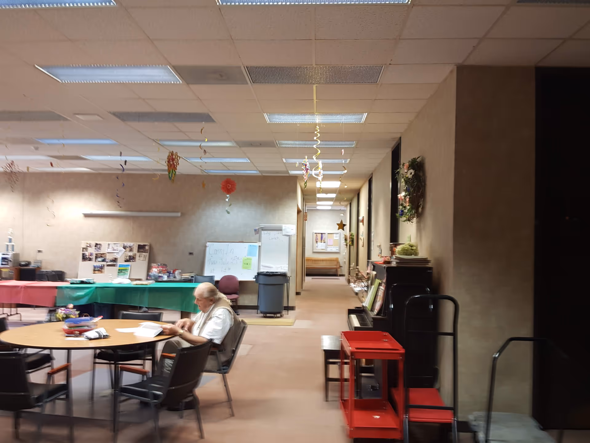 Long hallway in a senior facility with a round table, chairs, and festive decorations.