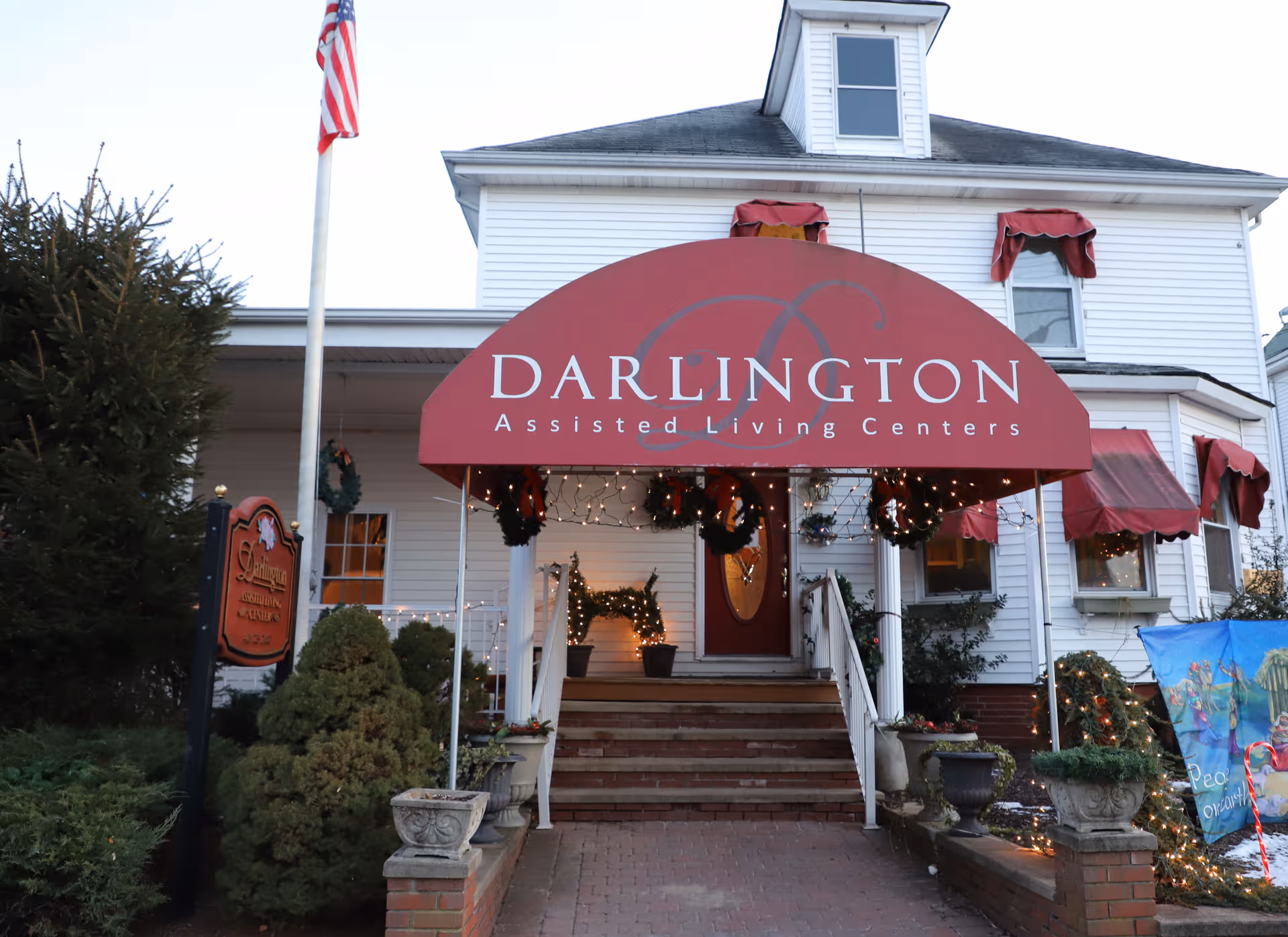 Front entrance of Darlington Assisted Living Centers with red awning and holiday lights.