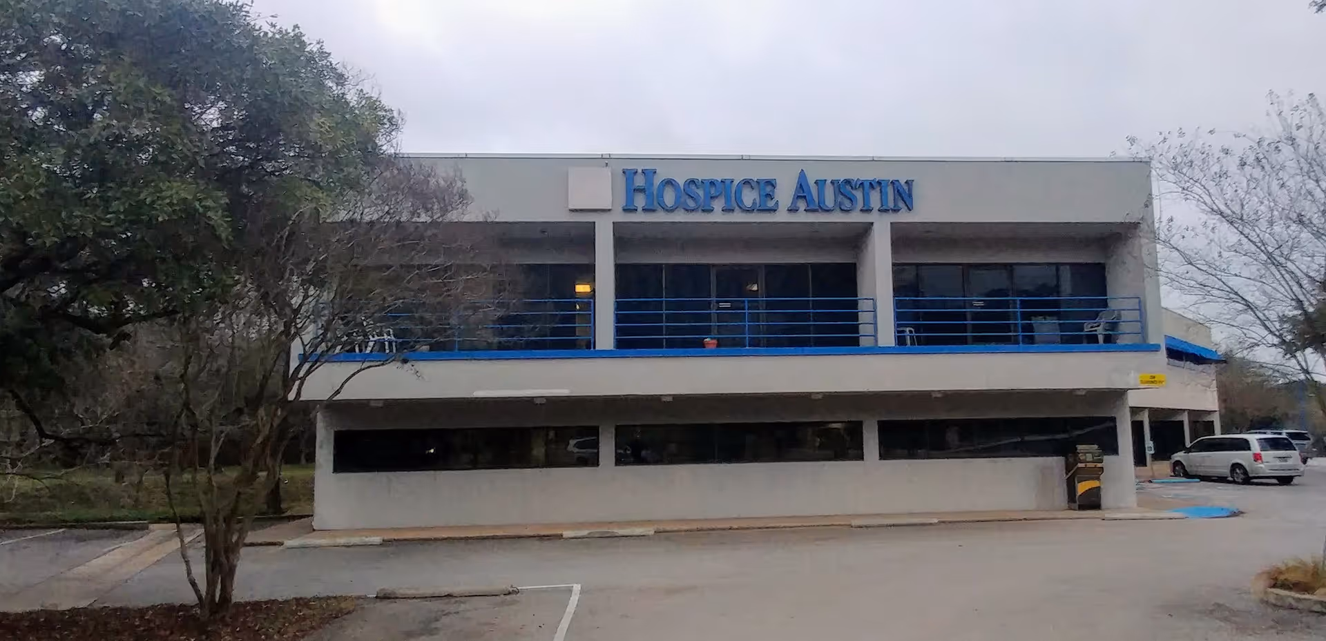 Two-story Hospice Austin building exterior with blue railing and sign