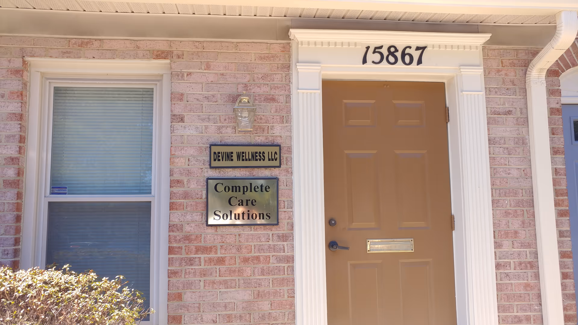 Exterior brick building entrance with brown door and signage reading Complete Care Solutions.