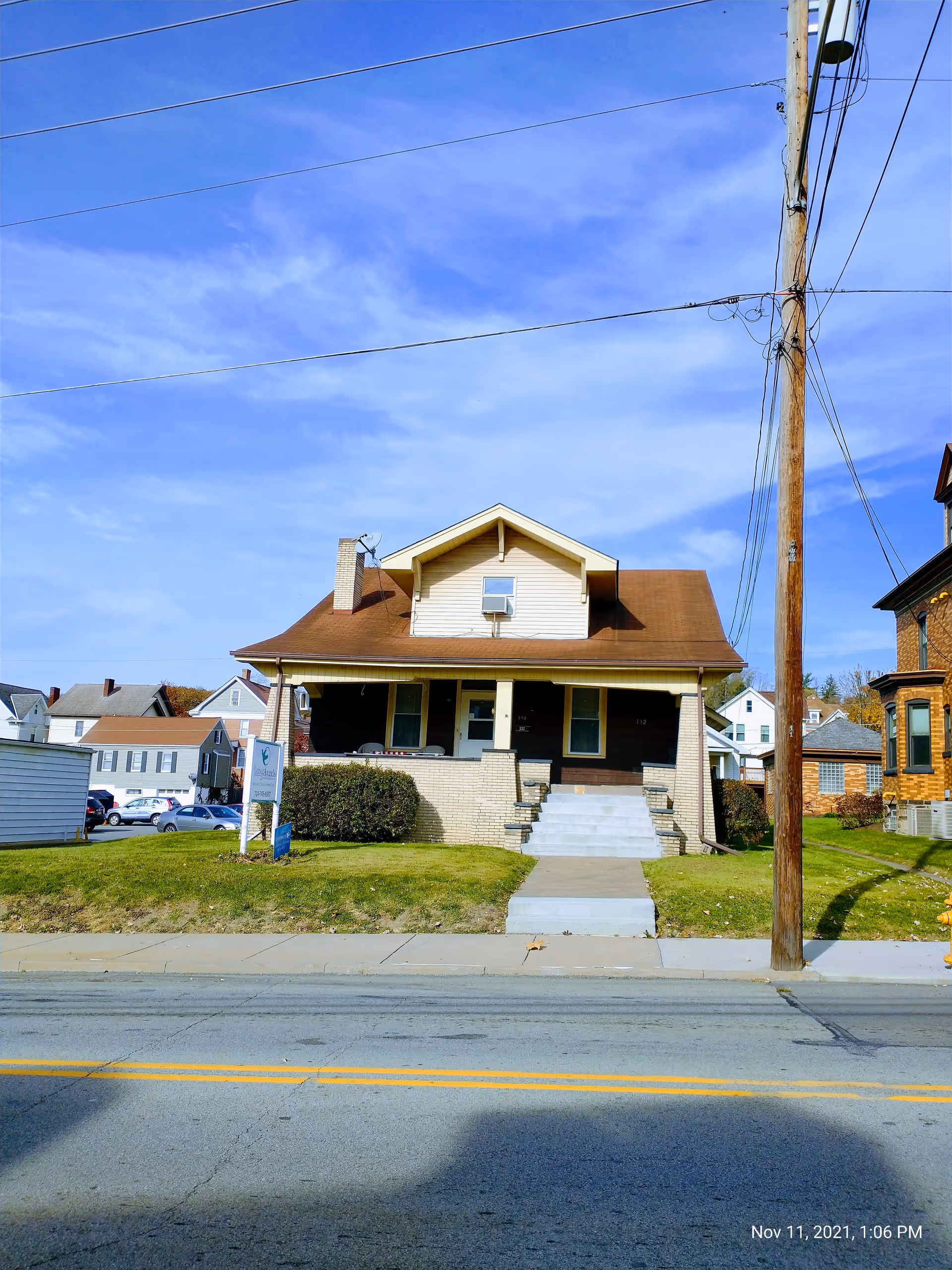Front view of a single-story house with a porch, steps, and a grassy lawn.