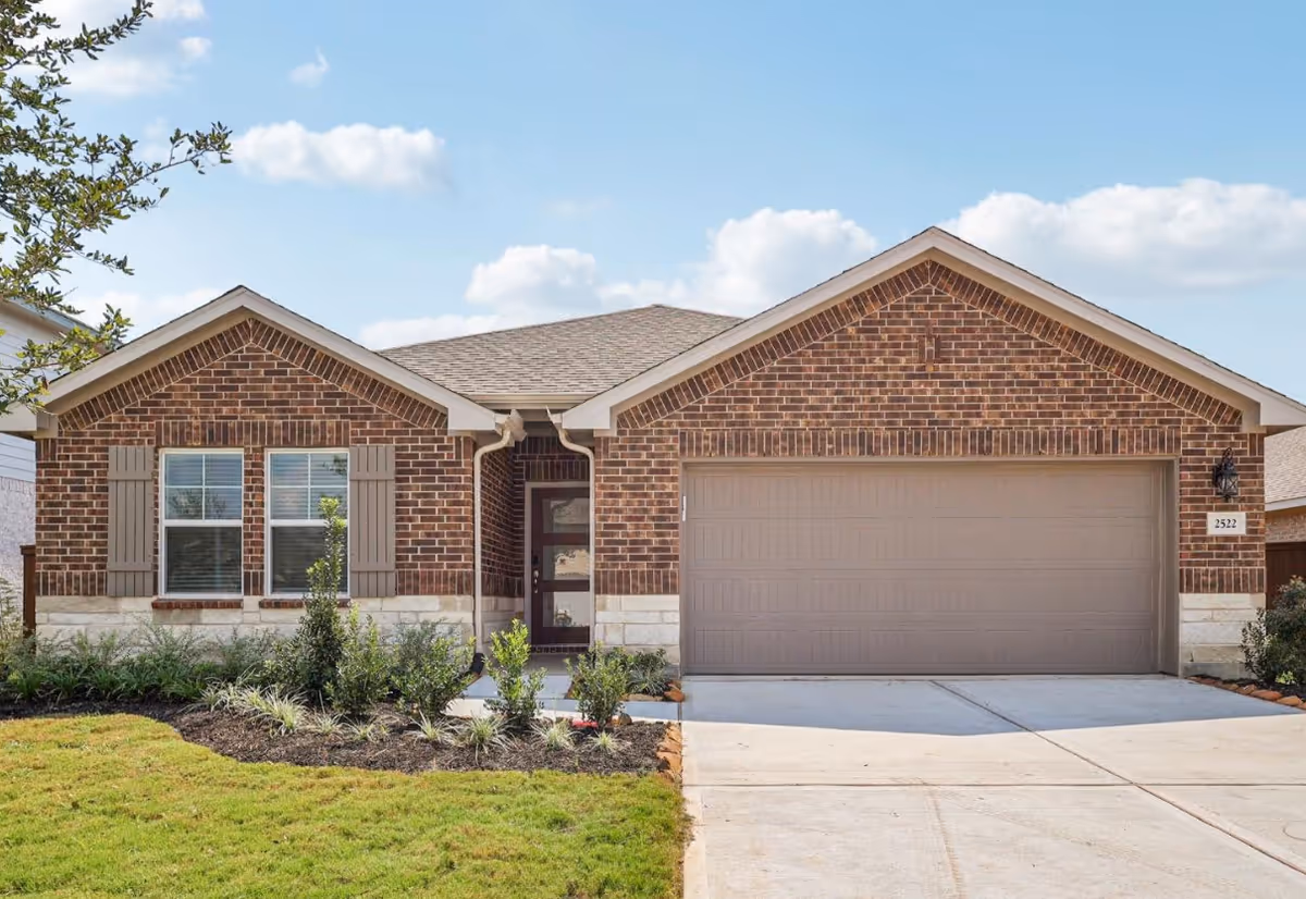 Brick suburban house with two-car garage and manicured front yard.