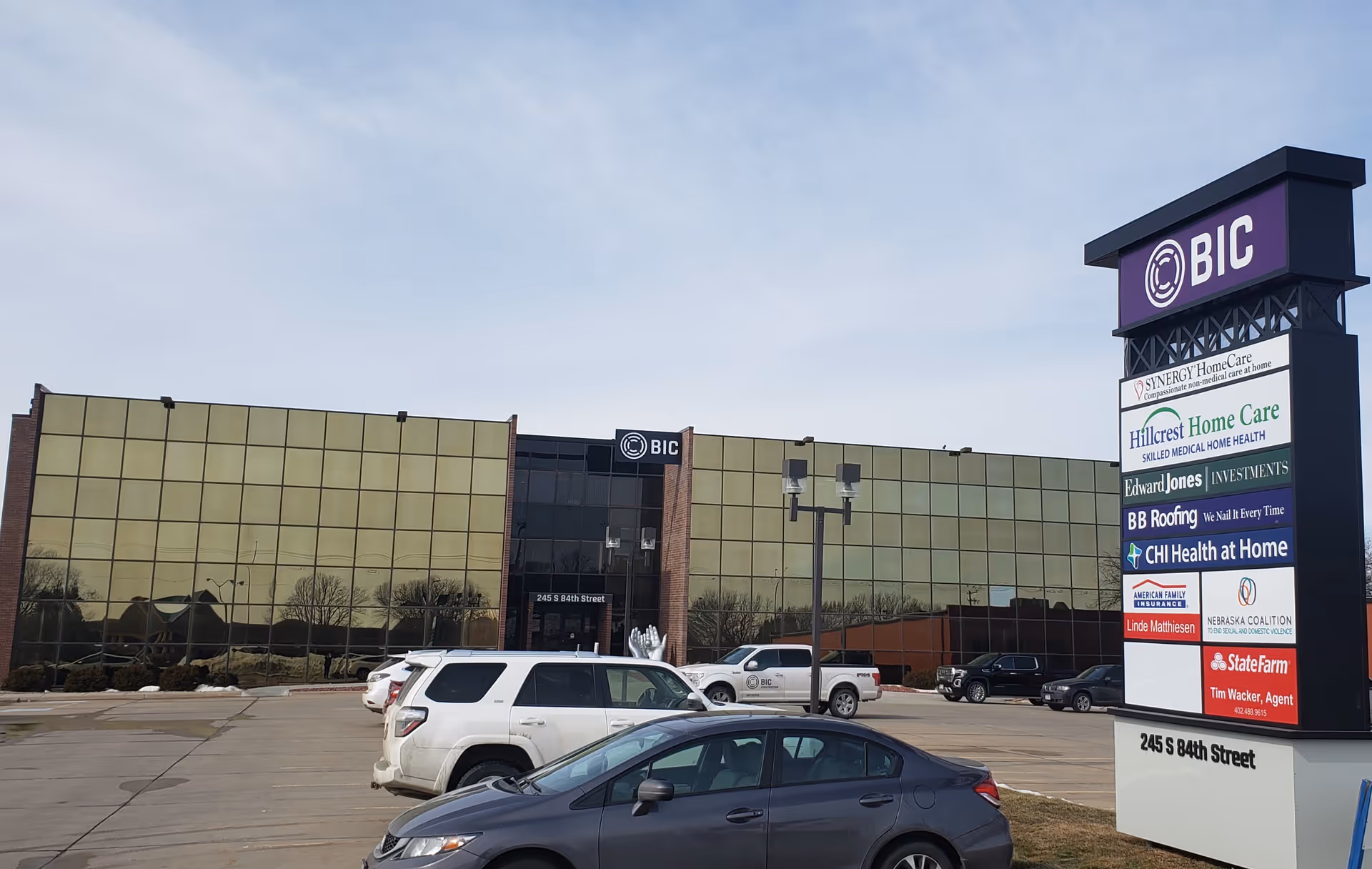 Exterior view of a commercial building with a tall Hillcrest Home Care sign and parked cars