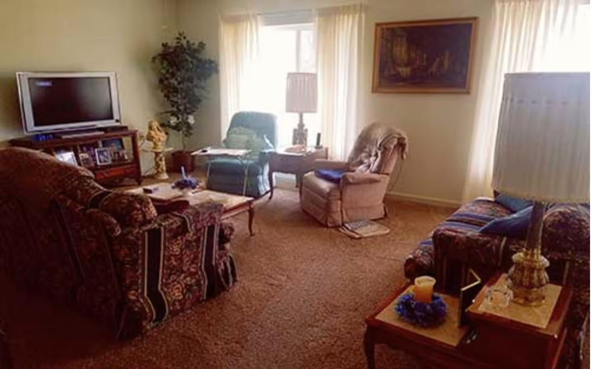 Cozy living room in Regency Retirement Residence with sofa, recliners, coffee table, and TV.