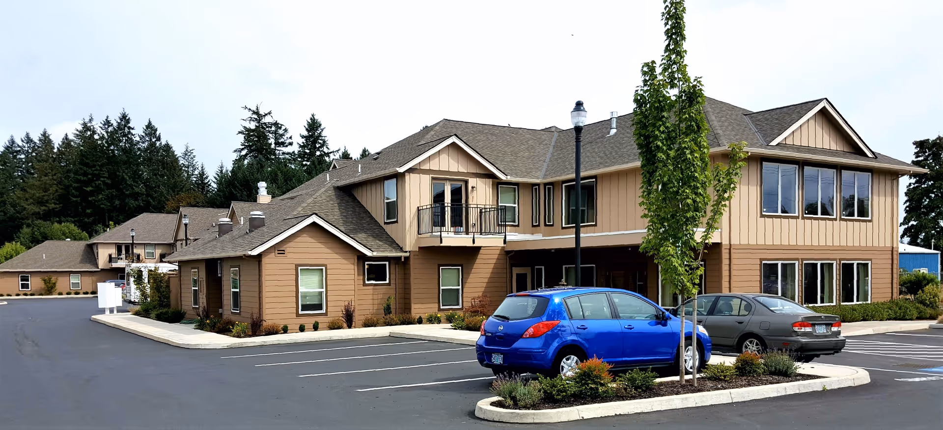 Exterior view of Fircrest Senior Living facility with brown siding, parking, and landscaping.