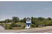 Outdoor view of North Roanoke Assisted Living sign beside road with trees and fence
