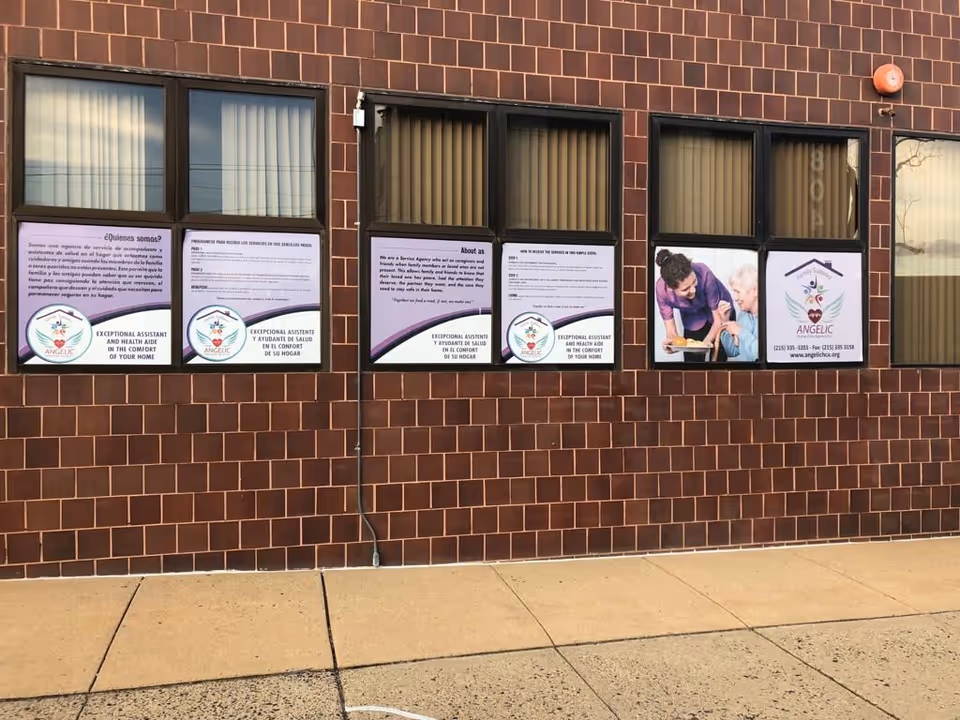 Brick building exterior with multiple windows displaying posters for Angelic Home Care Agency Inc.