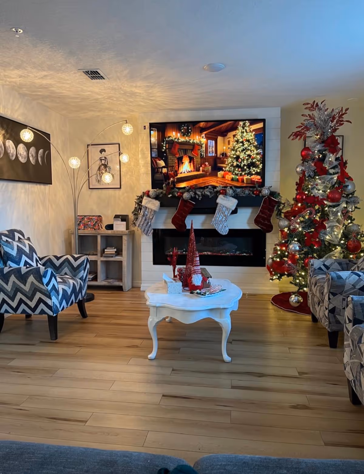 Cozy living room decorated for Christmas with a tree, stockings, fireplace, and TV.
