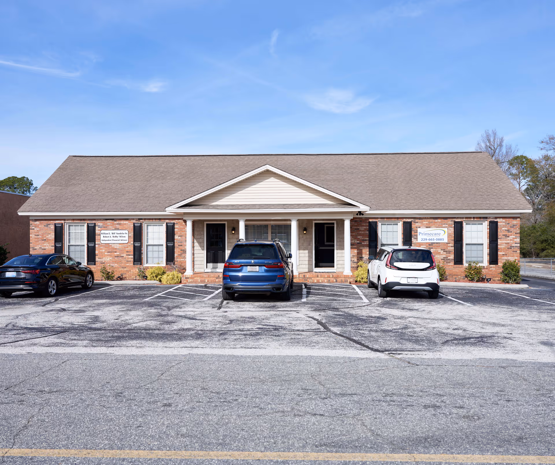 Front view of a brick Primecare Home Care Services building with cars parked outside.