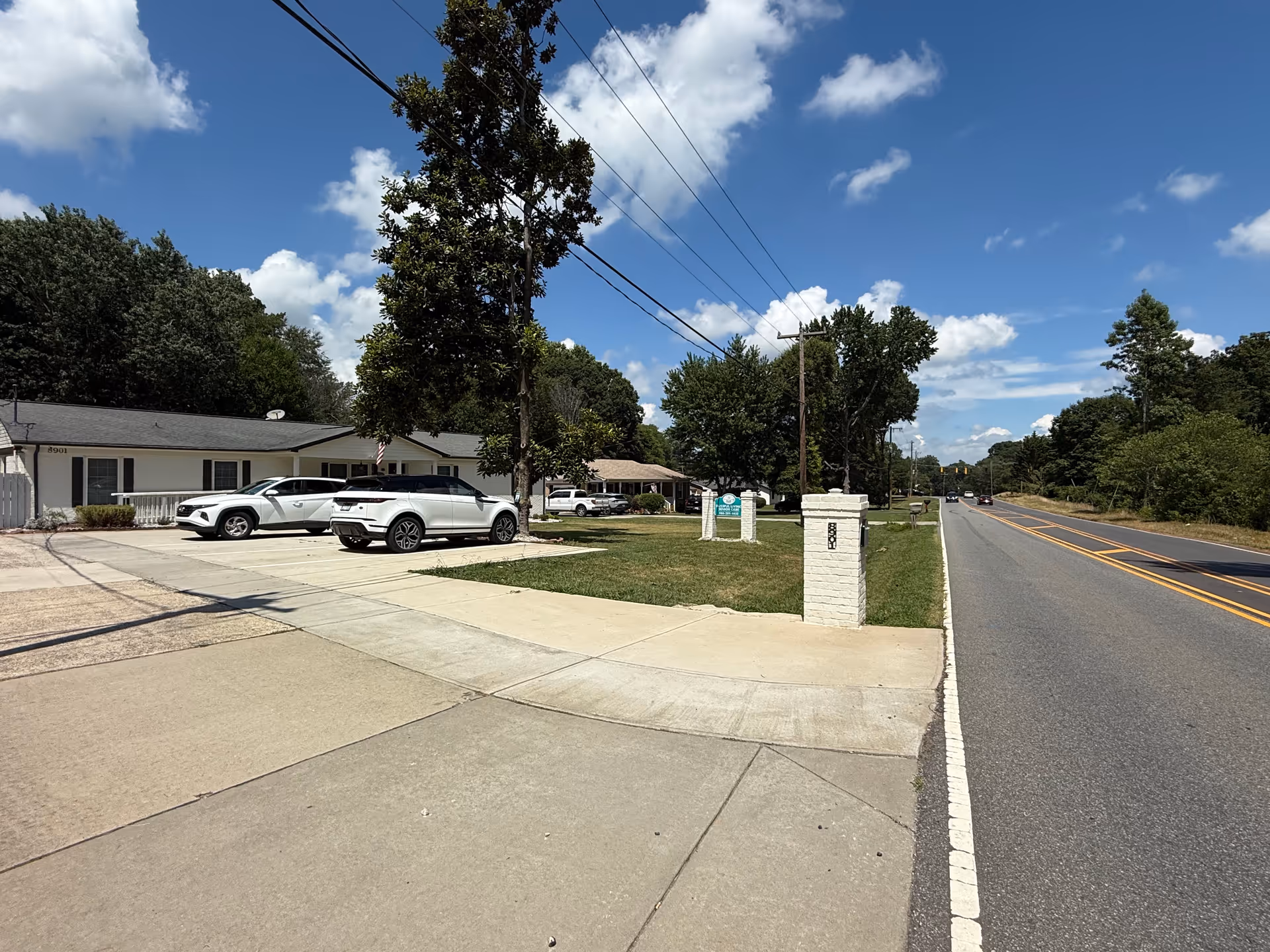 Front exterior of a single-story senior care facility with cars in the driveway.