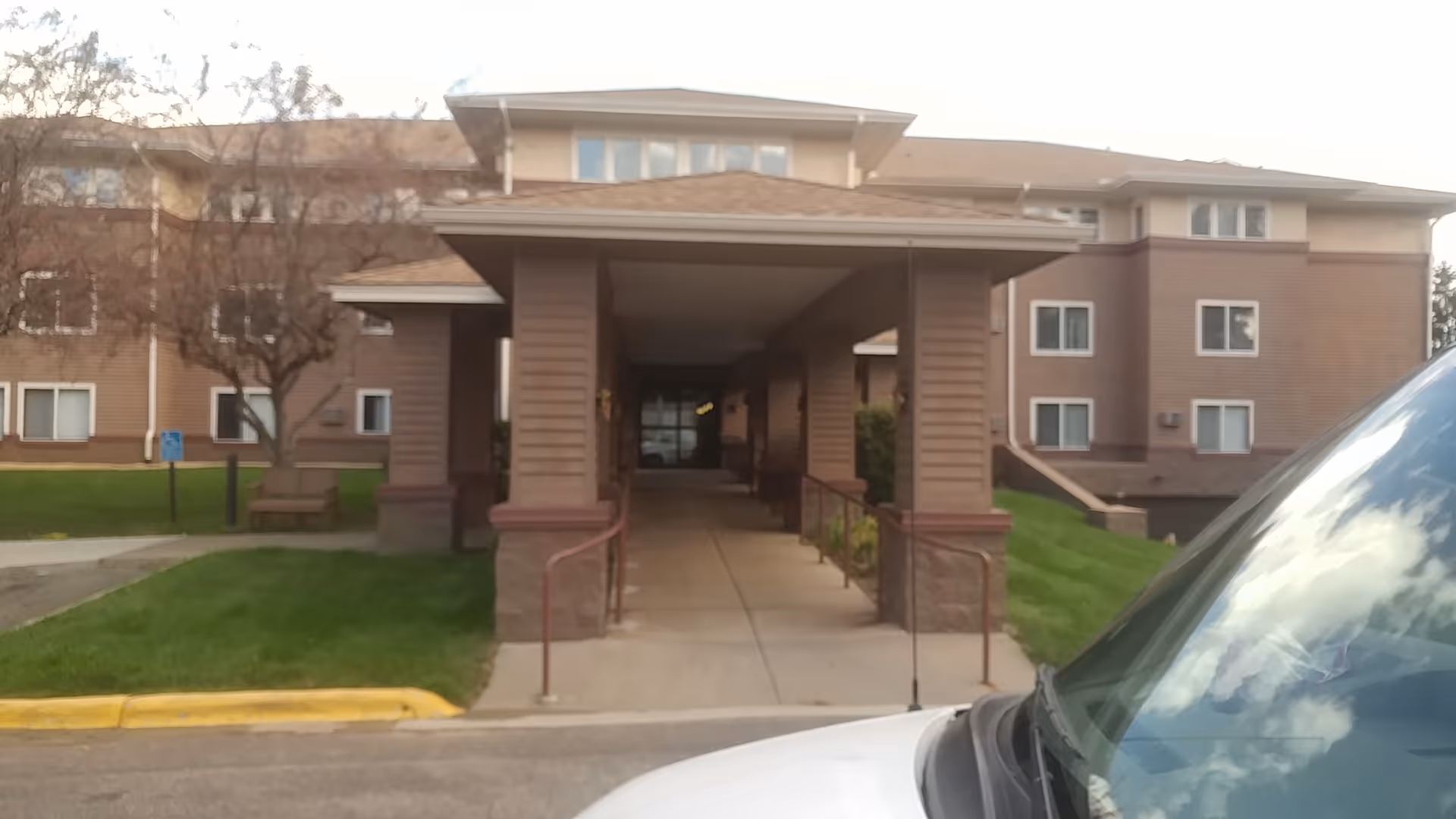 Front view of Brightondale Senior Campus entrance with a covered walkway and parked vehicle.