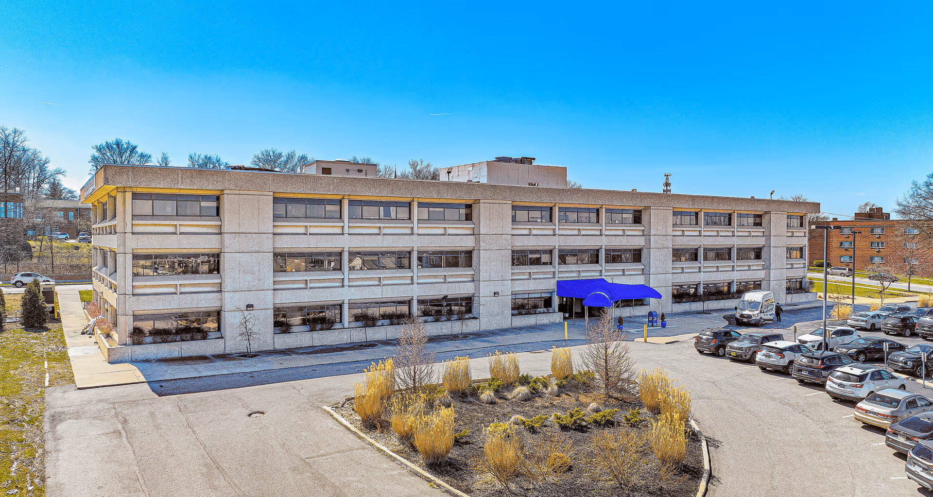 Exterior view of AllianceOne HealthCare building with blue canopy and adjacent parking lot.