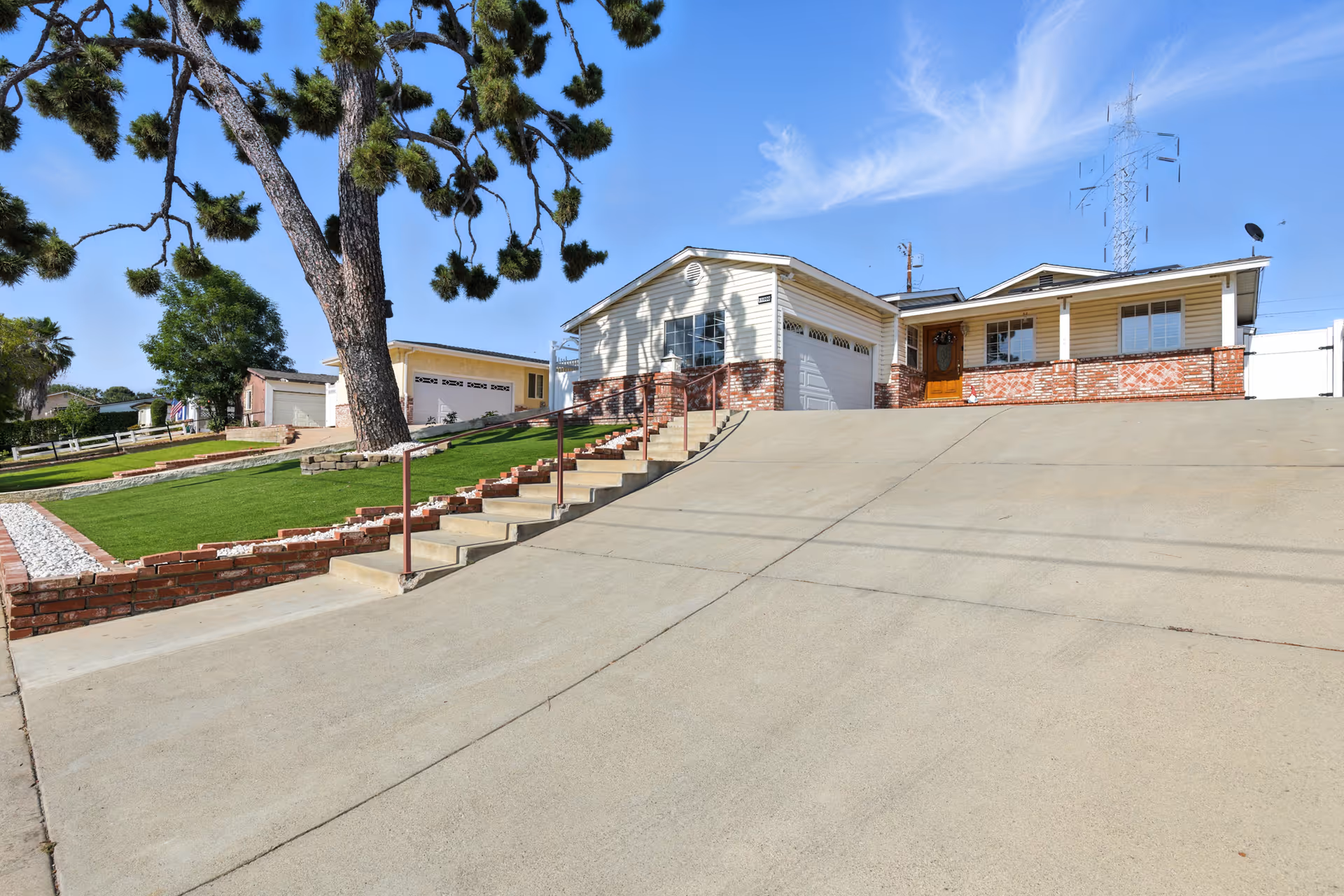 Exterior view of Integrity Assisted Living building with driveway, stairs, and lawn under a blue sky.
