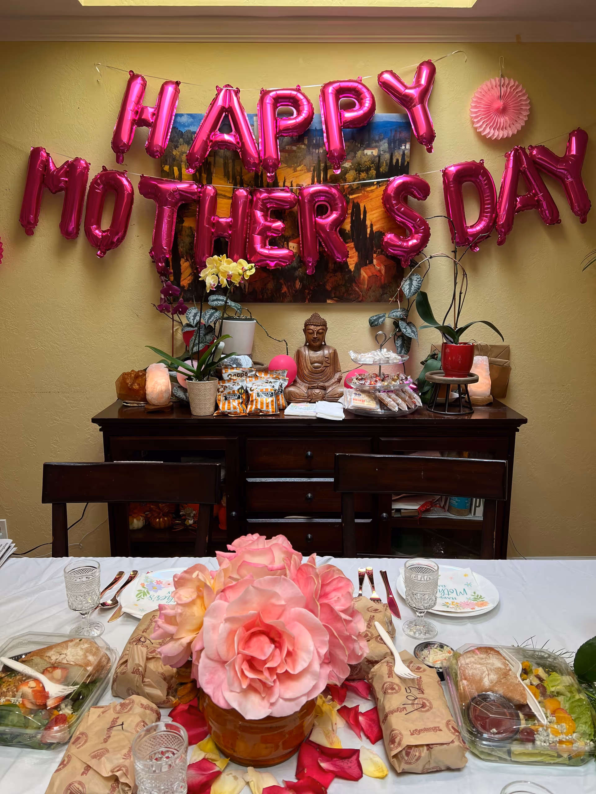Mother's Day balloons decorate a dining room table with flowers and treats.