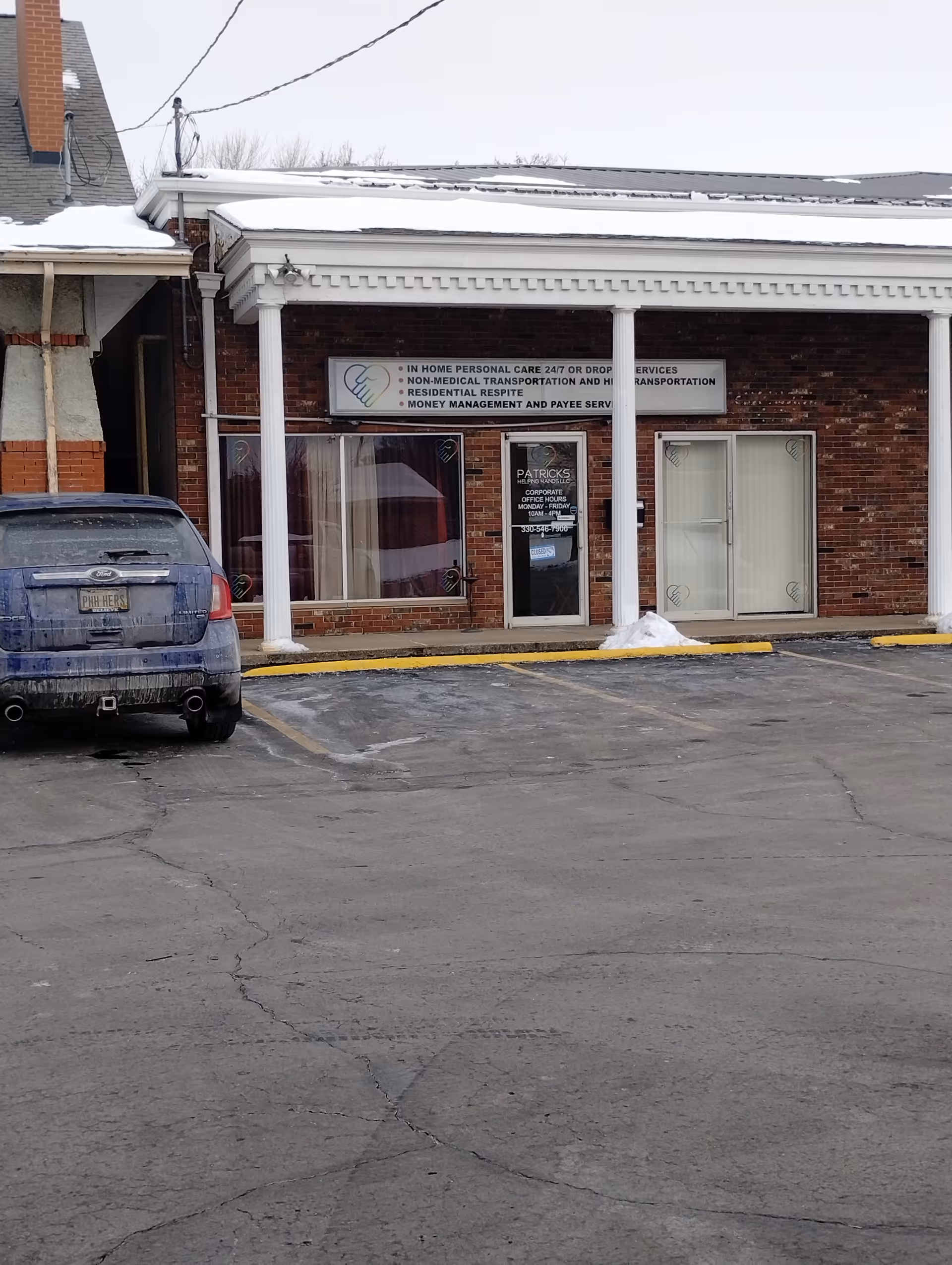 Brick storefront with Patrick's Helping Hands LLC signage and a blue SUV parked outside.