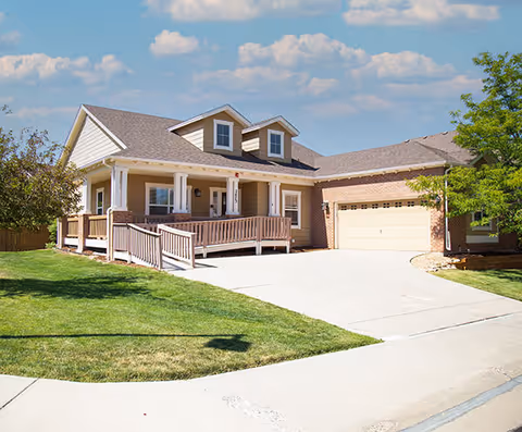 A senior living facility exterior with a front porch and two-car garage.