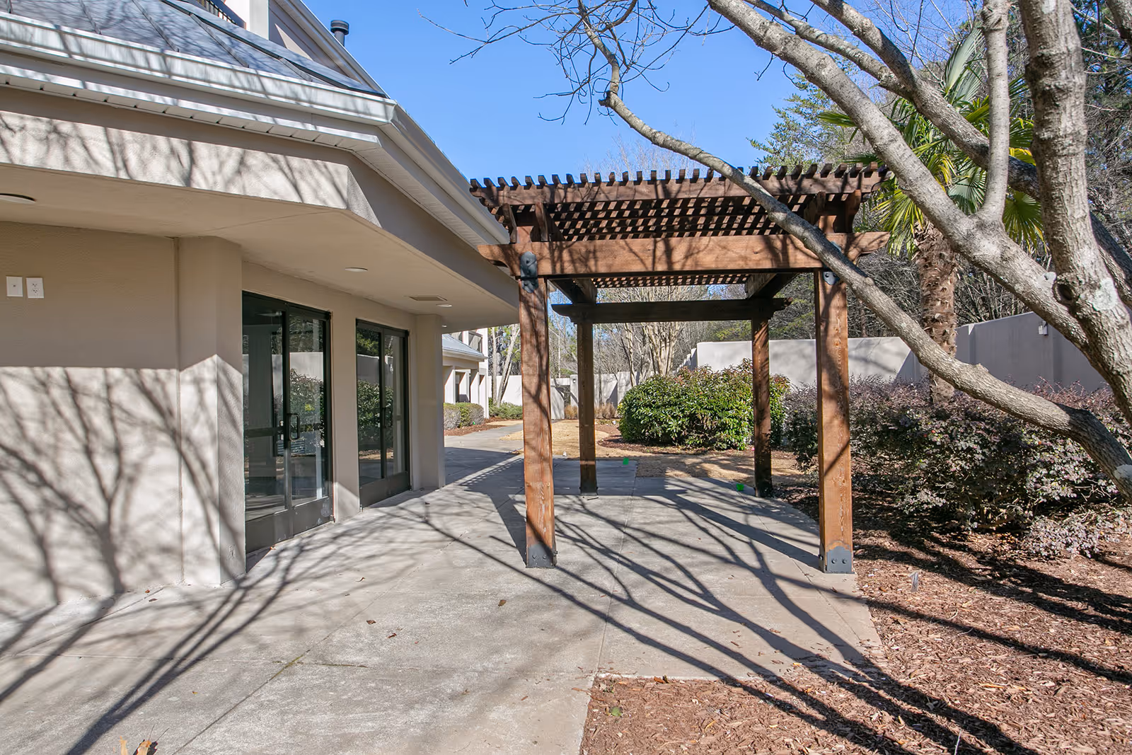 Exterior view of Spring House at Lithia Springs with glass doors, wooden pergola, and trees.