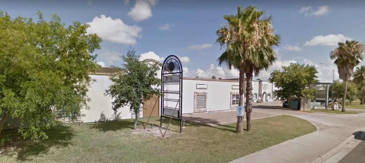 Exterior view of a senior living facility with palm trees and a play structure.