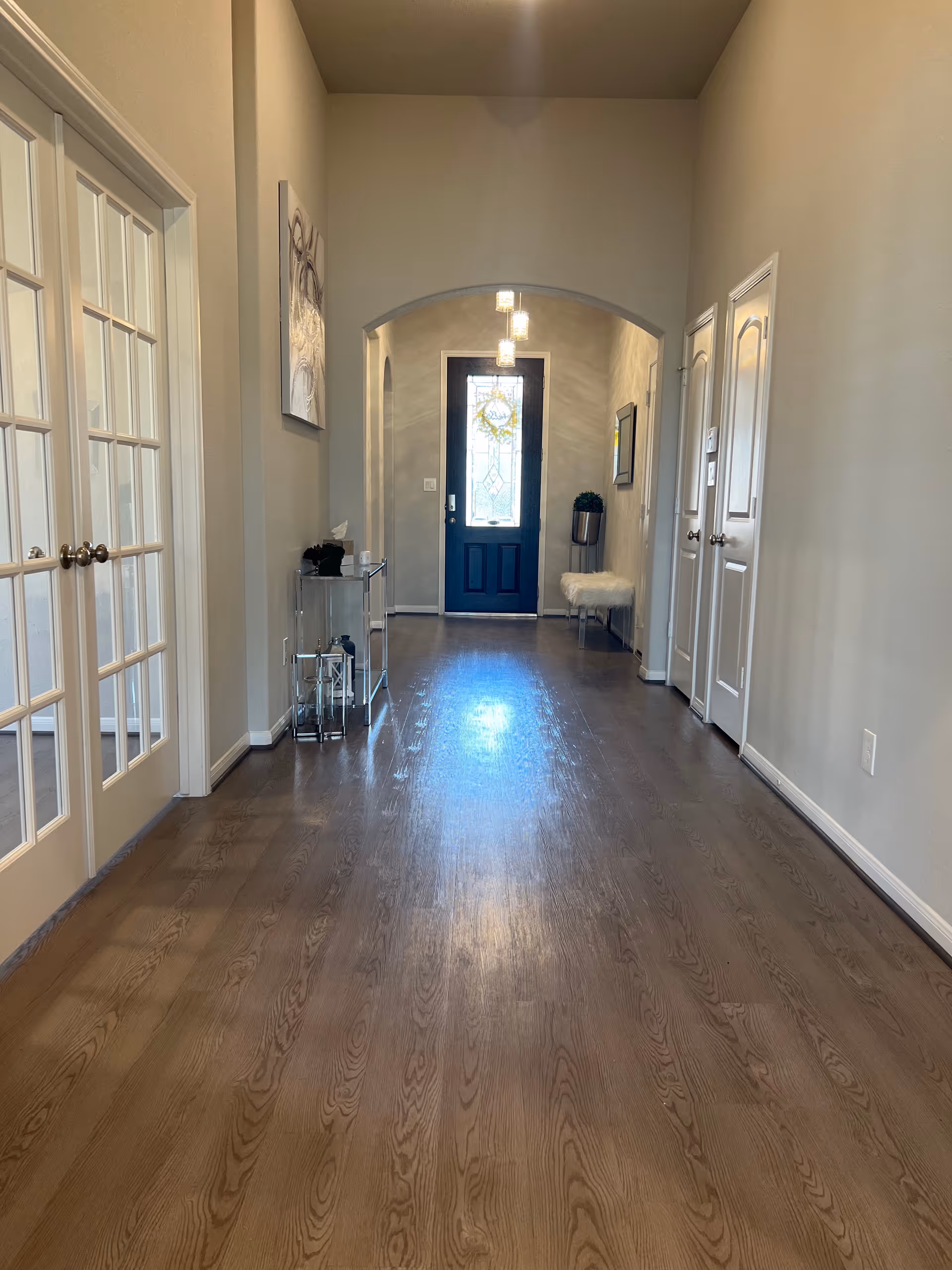 Wide hallway in a senior living facility with doors, arches, and a blue front entry.