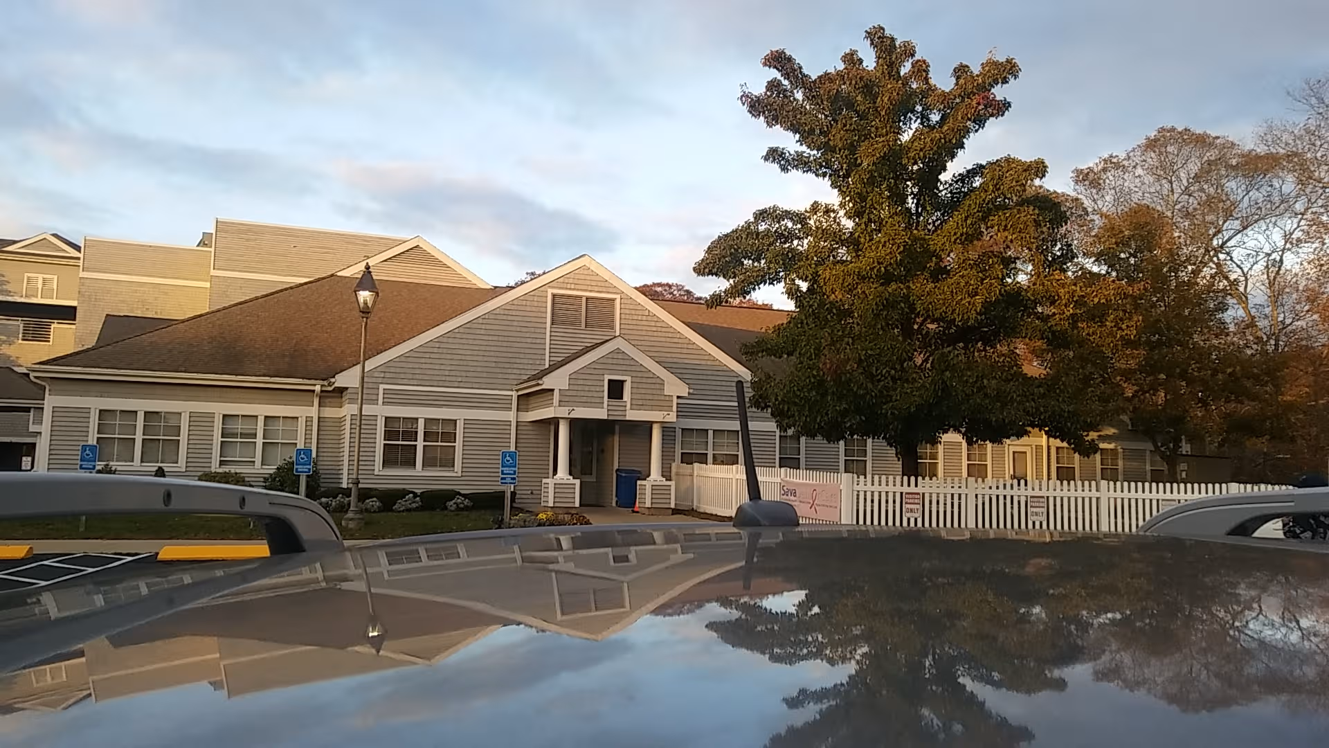 Exterior view of Bride Brook Rehabilitation and Nursing Center with a front entrance, tree, and cars.